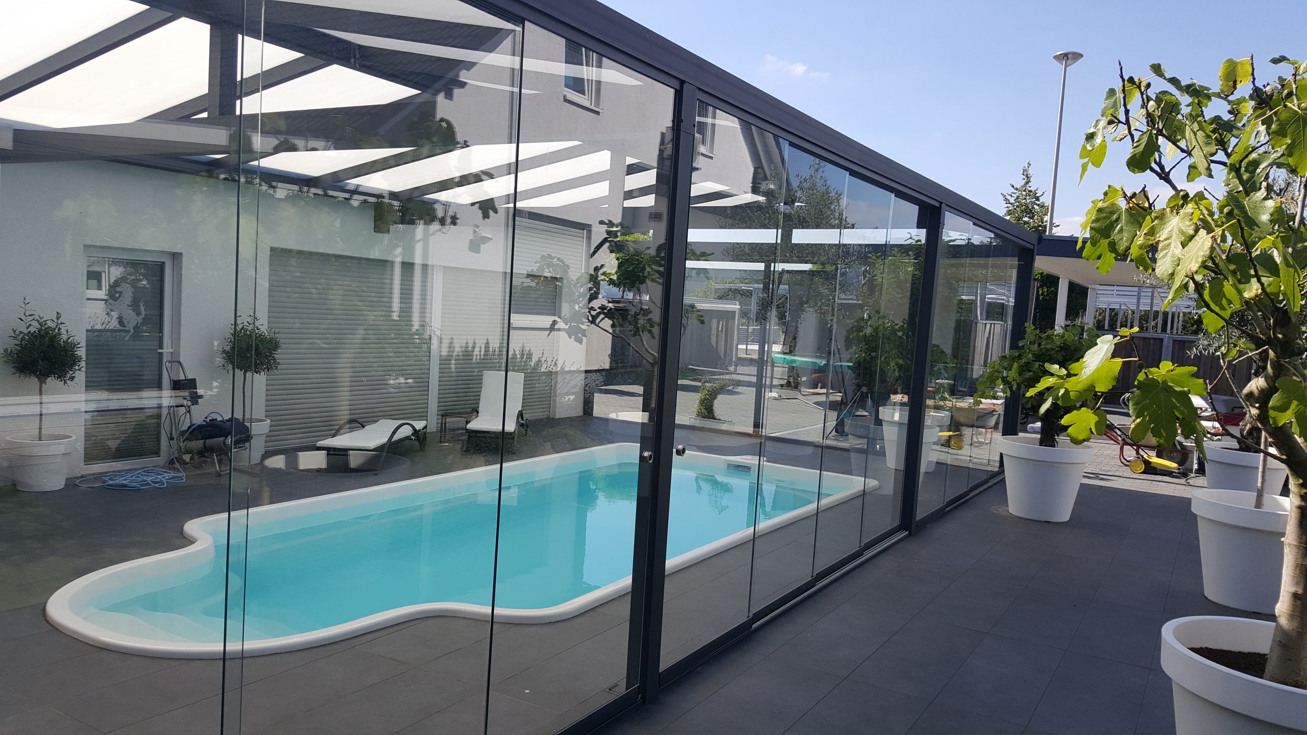 Modernes Terrassendach aus Aluminium mit Glaswänden neben einem Pool