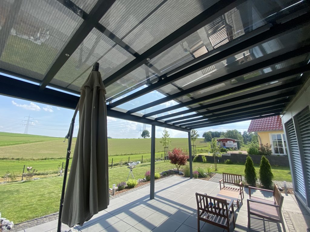Modernes Terrassendach mit Glasdach und integrierter Markise über einer Terrasse